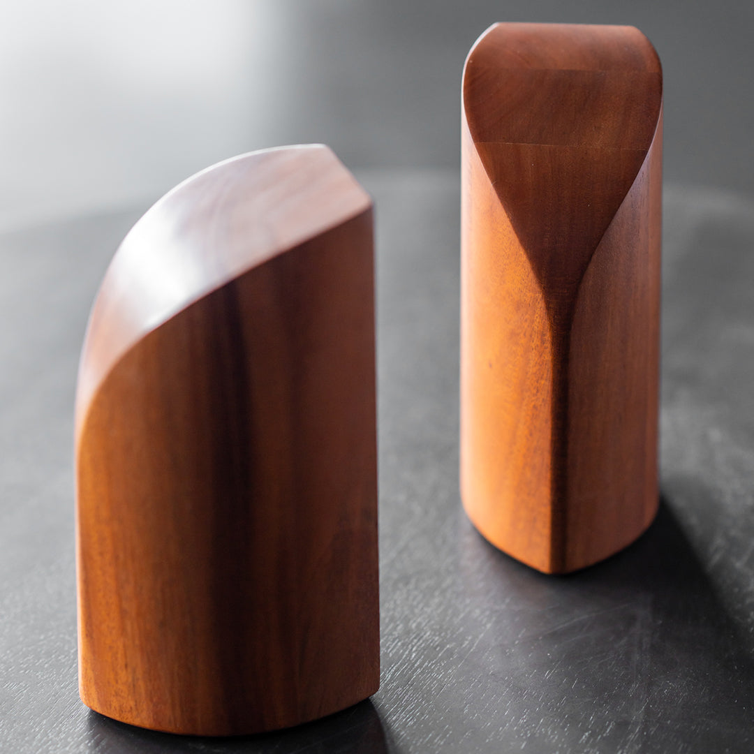 Smooth, polished wood bookends in rich brown tones, featuring elegant curved and angled designs.