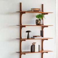 Brown wooden shelving unit with clean lines and smooth surfaces, accented by green plants and decorative items.