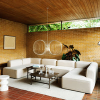 Modern beige sectional sofa with sleek lines in a cozy, earthy-toned living room with wood and brick accents.