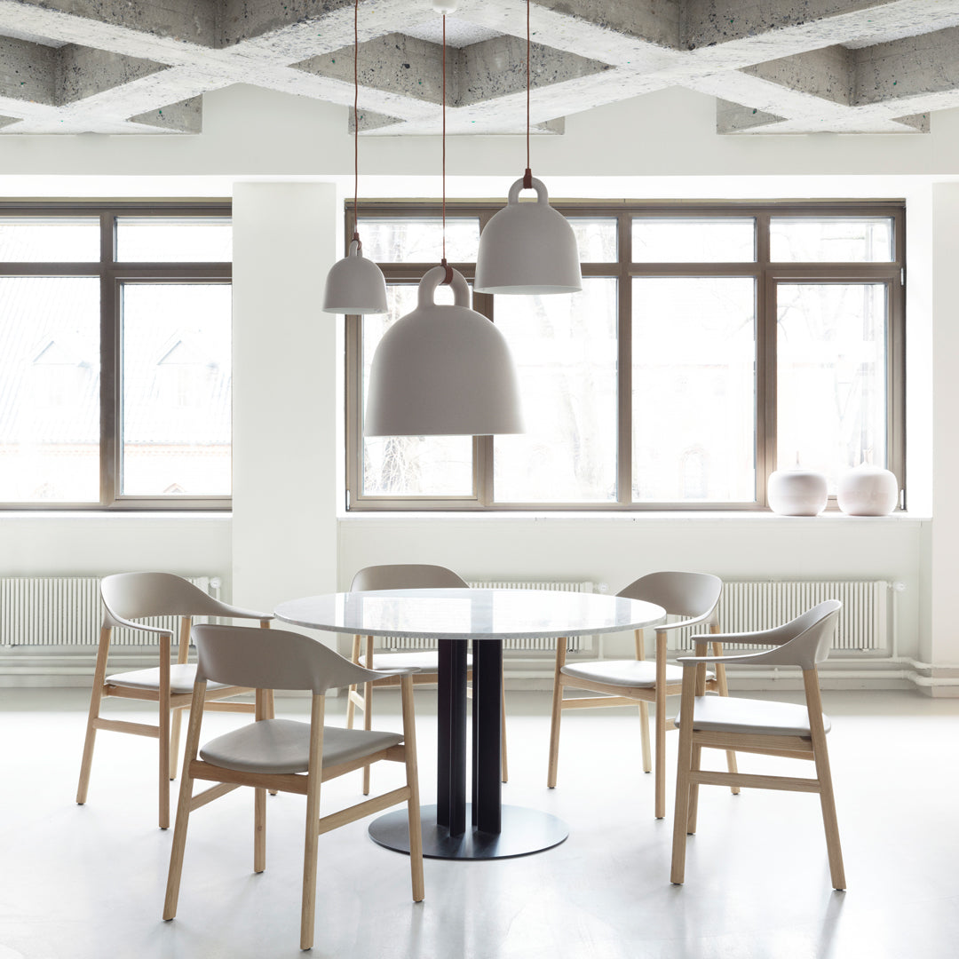 Modern dining set featuring a white table, light wooden chairs, and gray pendant lights against a bright, minimalist space.