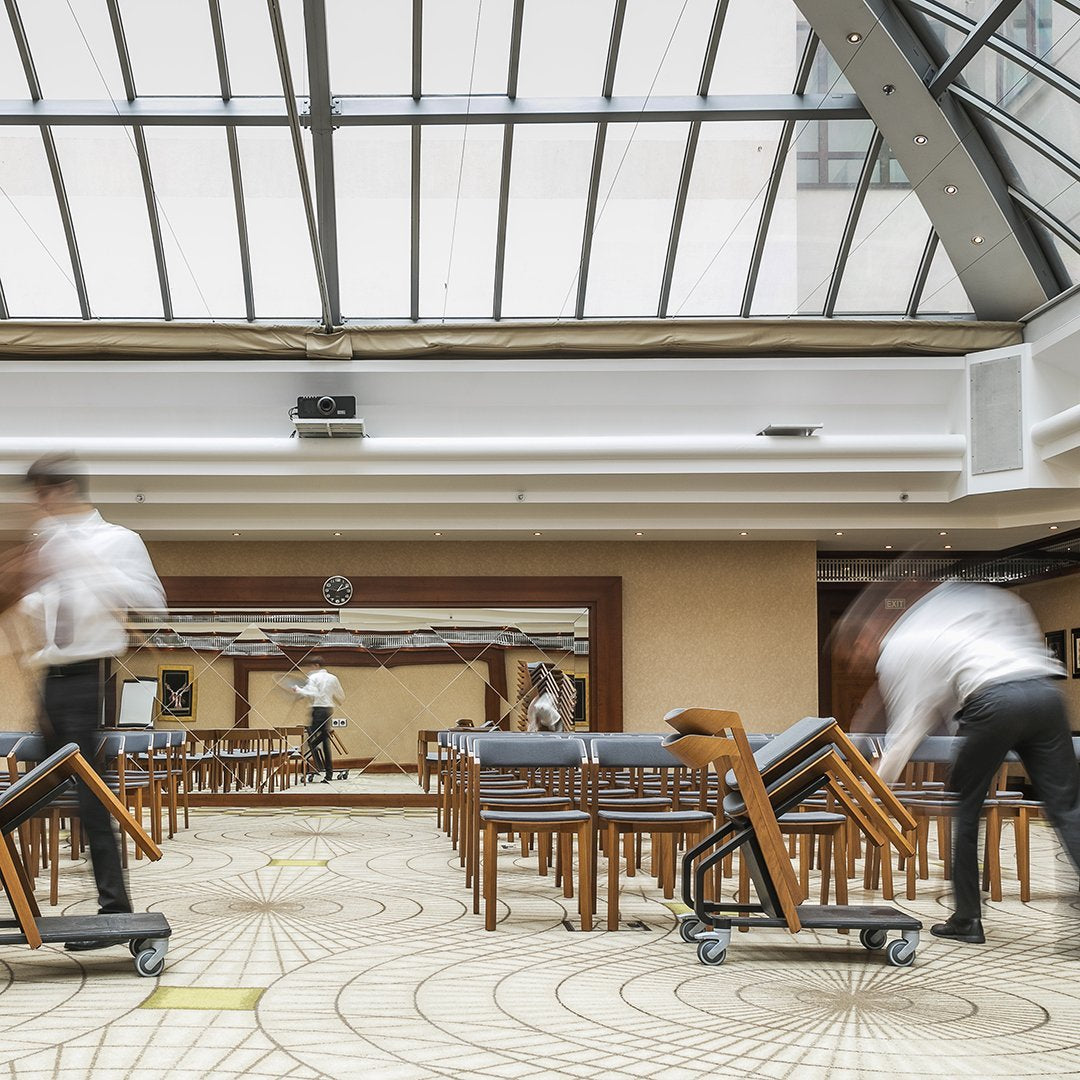 Elegant wooden chairs with gray upholstery set against a patterned floor and bright, airy skylight ambiance.