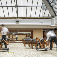 Elegant wooden chairs with gray upholstery set against a patterned floor and bright, airy skylight ambiance.