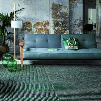 "Modern living room featuring a blue sofa, green decor, and a textured green patterned rug."