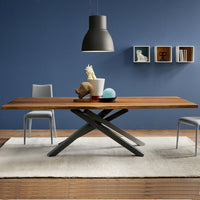 Wooden dining table with a dark brown finish, black metal base, gray chairs, and blue wall, set on a soft white rug.