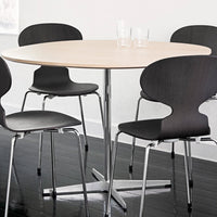 Scandinavian-style round table with a light wood top and sleek black chairs featuring a smooth finish and chrome legs.