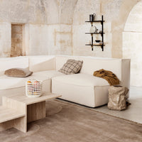 Beige sectional sofa with plaid and solid throw pillows, light wood coffee table, and textured beige rug.