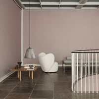 Modern interior featuring soft pink walls, sleek gray furniture, and natural stone flooring with minimalist decor elements.
