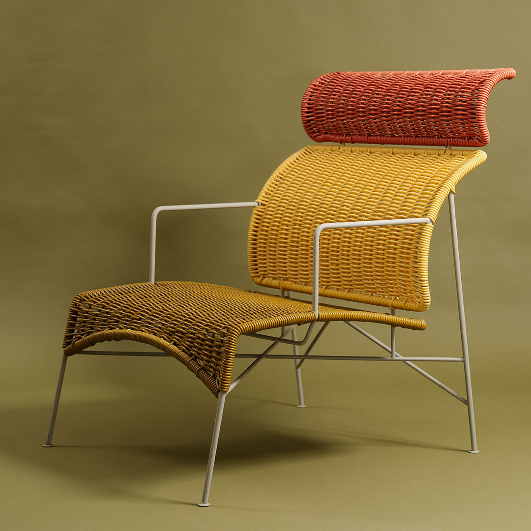 Stylish chair featuring a vibrant yellow and red woven pattern on a sleek metal frame against a soft green background.