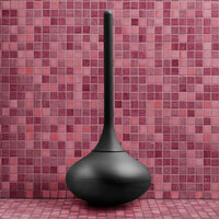 Black minimalist vase against a vibrant pink mosaic tile background, highlighting smooth curves and bold contrast.