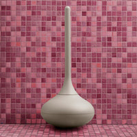 Beige modern vase against a vibrant pink mosaic tiled background, featuring varied shades and patterns.