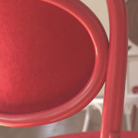 Close-up of a vibrant red chair with smooth curves and a textured surface, showcasing its bold color and distinctive design.