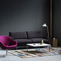Modern living room featuring a black sofa, purple chair, and a multicolored striped rug on a gray floor.