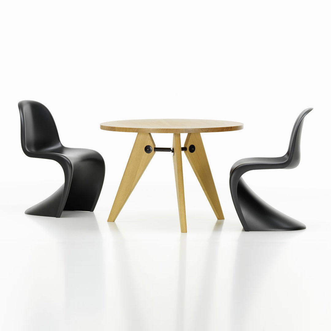Modern round wooden dining table with natural finish and unique black curved chairs, showcasing a minimalist design.
