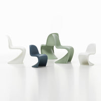 Assorted modern chairs in white, green, navy, and light gray, showcasing sleek curves and minimalist design.