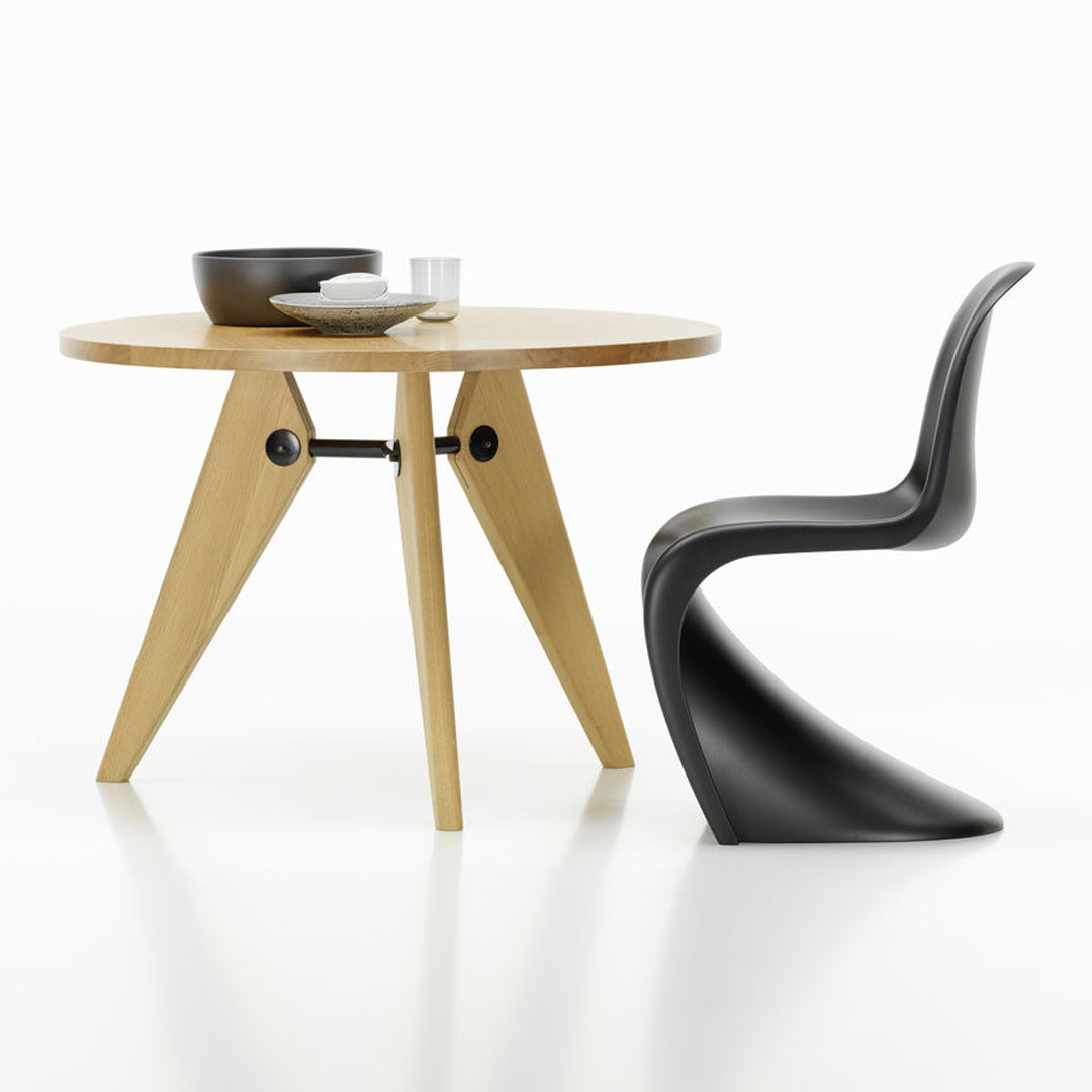 Modern wooden table with natural finish and black sculptural chair. Minimalist design showcasing clean lines and contrasting colors.