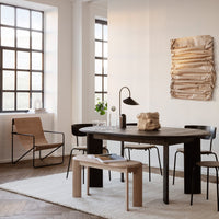 Neutral tones with soft textures; minimalist wooden table, black chairs, and earthy artwork create a modern atmosphere.