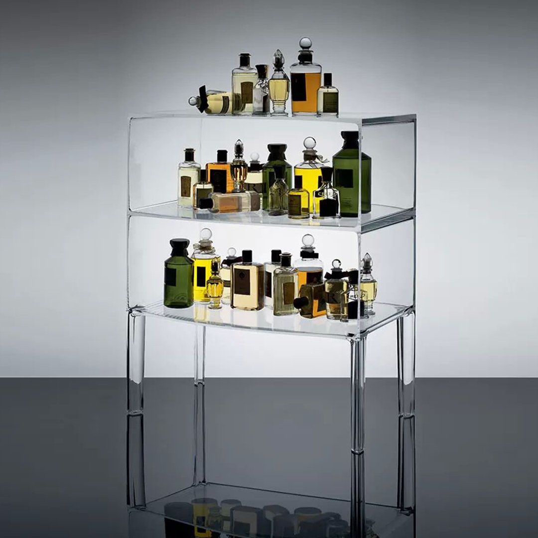 Clear acrylic display with vibrant amber, green, and golden perfume bottles in various shapes. Modern and elegant design.
