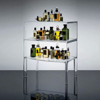 Clear acrylic display with vibrant amber, green, and golden perfume bottles in various shapes. Modern and elegant design.
