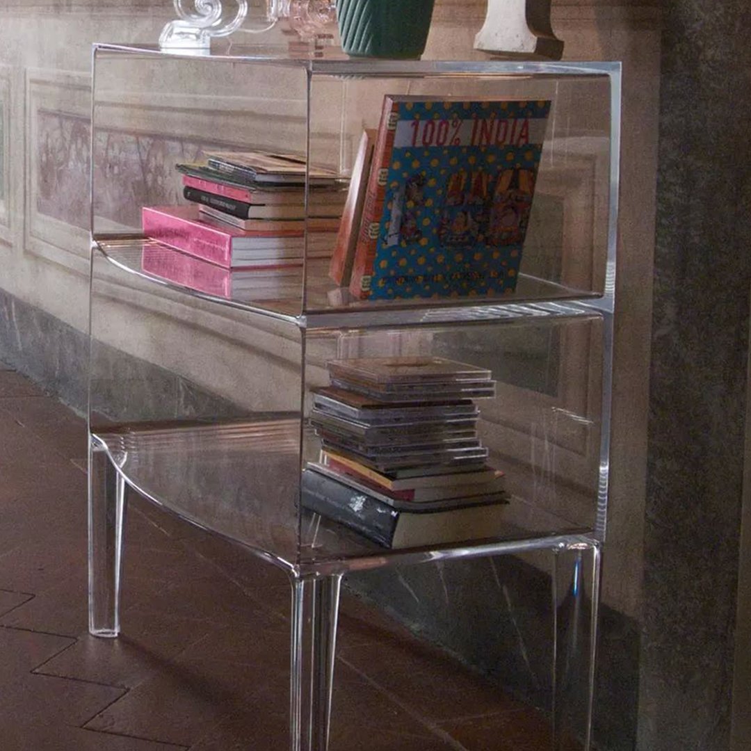Clear acrylic bookshelf showcasing colorful books and decorative items in a stylish interior setting.