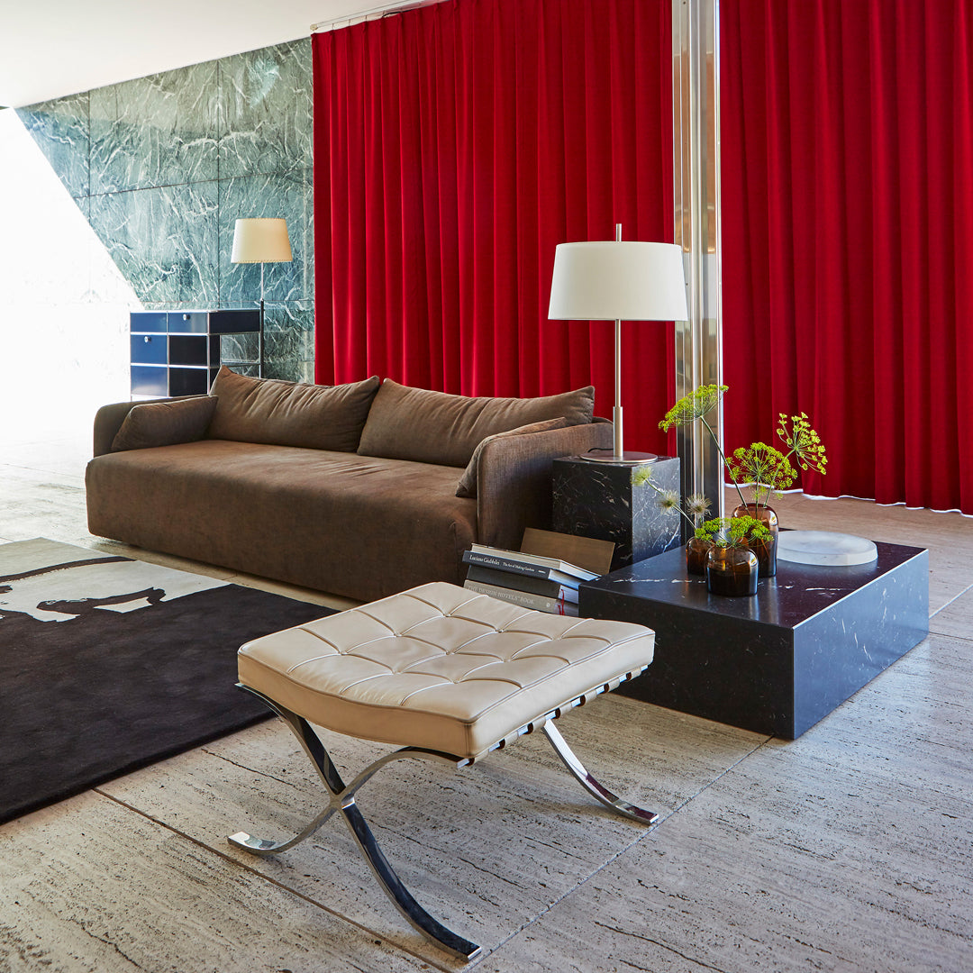 Brown sofa with a textured pattern, accented by red curtains and a black coffee table in a modern interior setting.