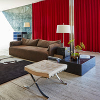 Brown sofa with a textured pattern, accented by red curtains and a black coffee table in a modern interior setting.