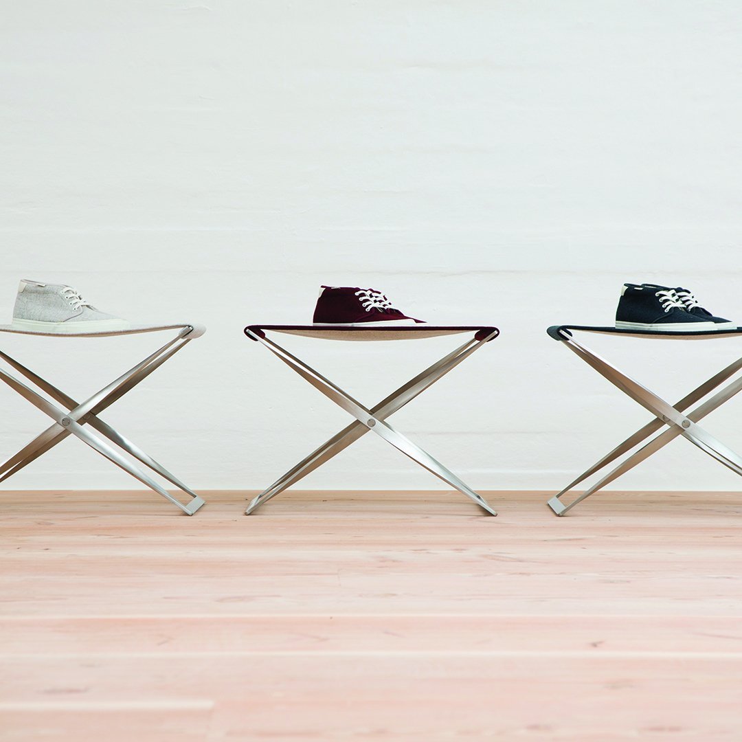 "Three pairs of sneakers in white, burgundy, and black displayed on sleek silver stools against a light background."