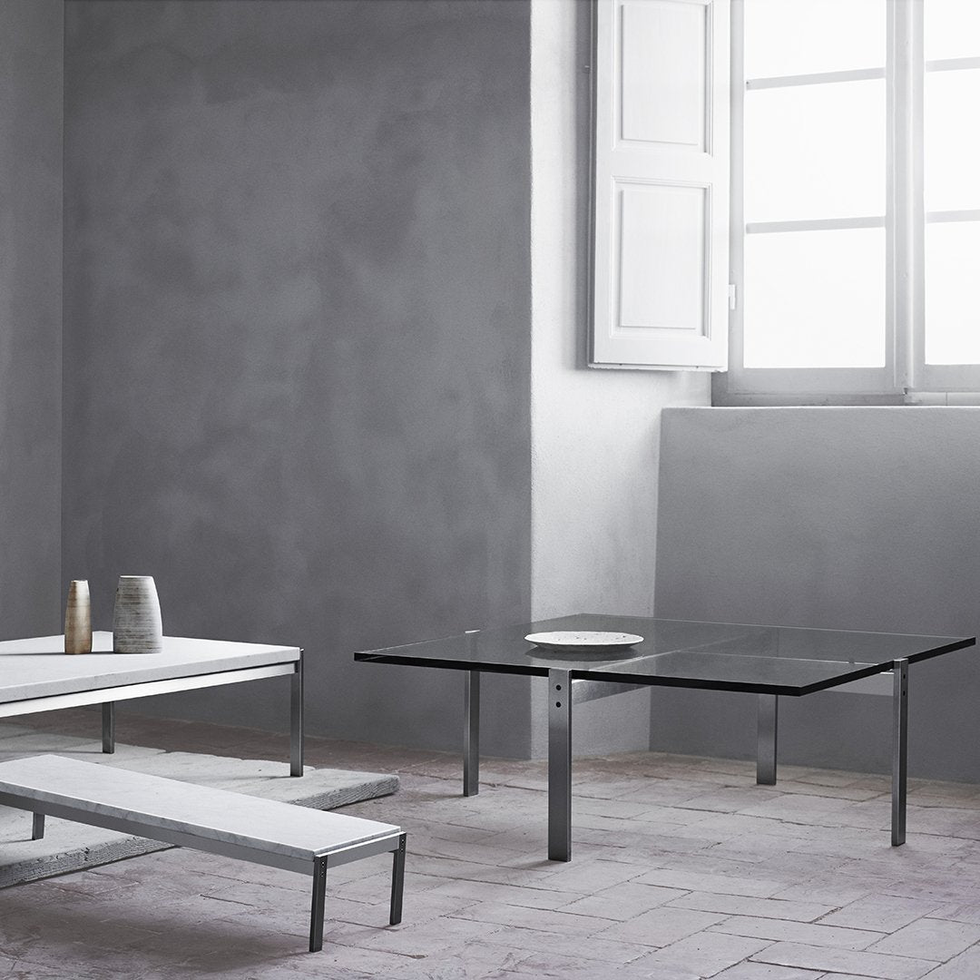 Minimalist gray and white furniture with sleek chrome accents, featuring a modern glass tabletop design.
