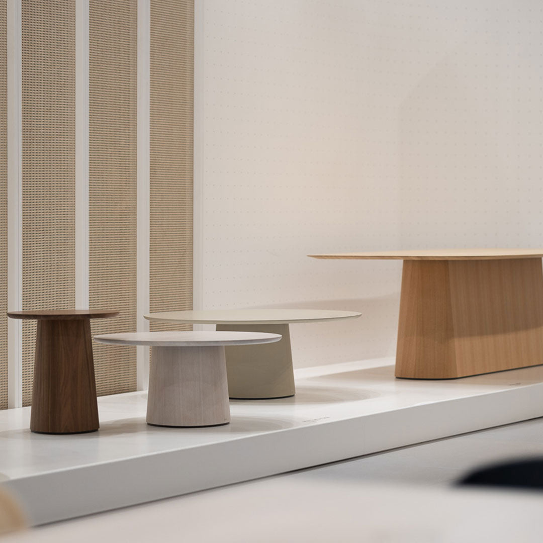 Set of three modern tables in natural wood tones: walnut, oak, and light grey with minimalist round tops.