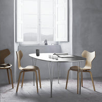 Modern oval dining table with a sleek gray surface and natural wood chairs in a minimalist, neutral-toned setting.