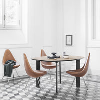 Brown curved chairs around a round wooden table on a black and white patterned tiled floor in a bright, minimalist room.