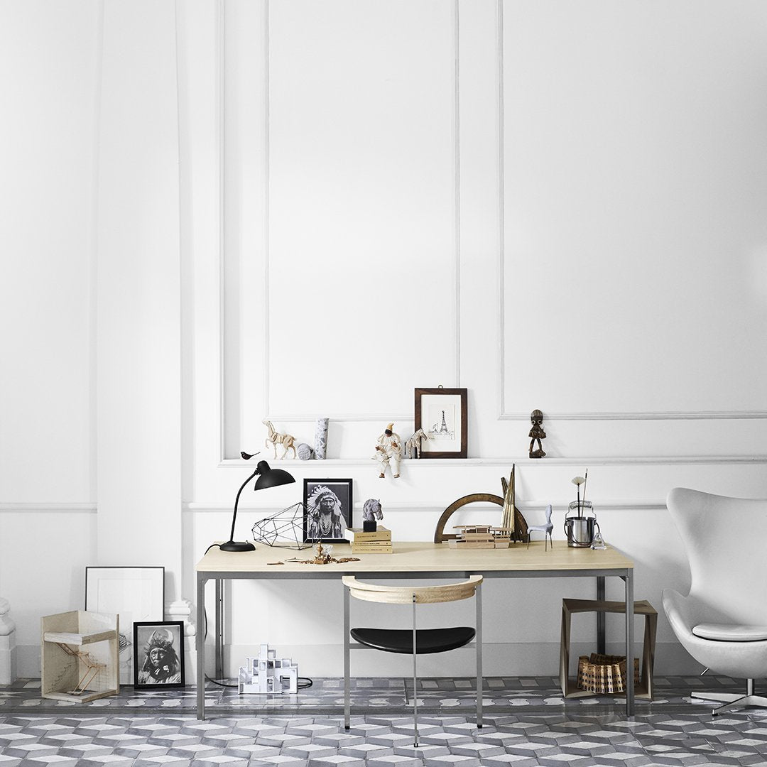 Minimalist white office space with gray geometric patterned rug and natural wood desk. Elegant black and white decor accents.