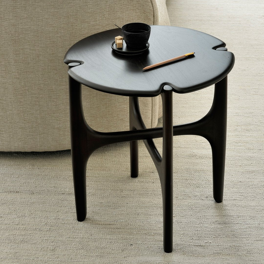 Black round side table with a smooth finish and unique petal-shaped edges, perfect for modern decor.