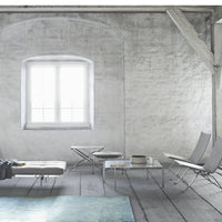 Neutral gray walls with light wooden accents and a soft blue area rug, creating a calm, modern atmosphere.