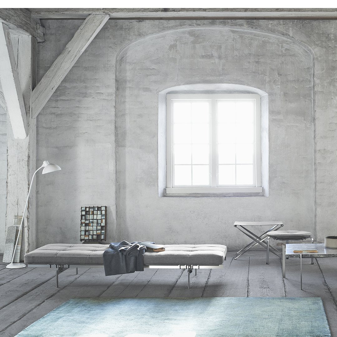 Minimalist interior featuring a soft blue rug, gray walls, and light wood accents, creating a serene atmosphere.