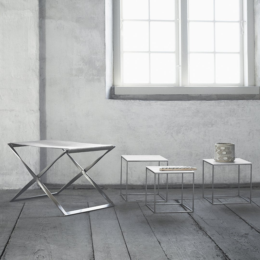 Set of four modern tables in sleek silver, white, and geometric patterns, against a minimalist gray background.