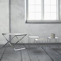 Set of four modern tables in sleek silver, white, and geometric patterns, against a minimalist gray background.