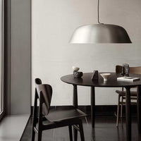 Modern black dining set with a sleek, metallic gray pendant lamp against a neutral wall. Clean lines and minimalist design.