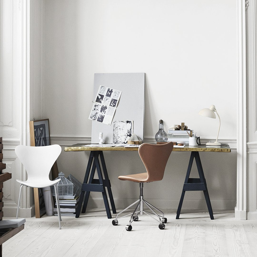 Modern desk setup featuring a brown and white chair, gold and navy accents, with a minimalist color scheme.