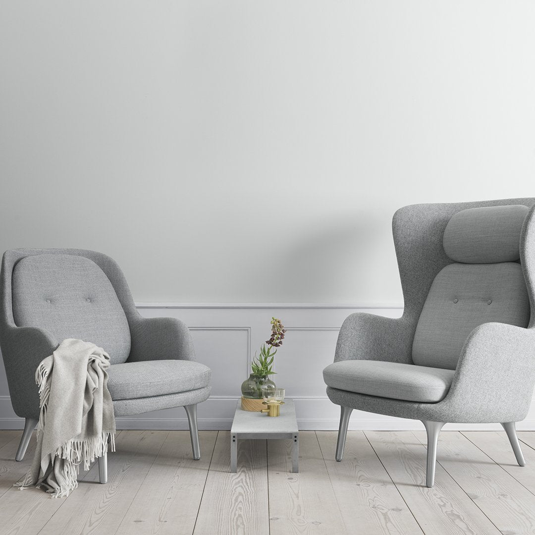 Gray upholstered armchairs with sleek lines, set on light wood flooring and paired with a minimalist white table.