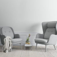 Gray upholstered armchairs with sleek lines, set on light wood flooring and paired with a minimalist white table.