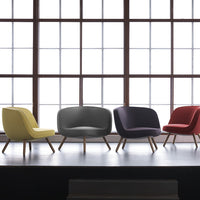 Colorful modern chairs in yellow, gray, purple, and red with sleek wooden legs against a bright window backdrop.