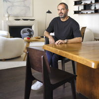 Black t-shirt with a minimalist design, paired with dark wooden furniture and a neutral-toned interior setting.