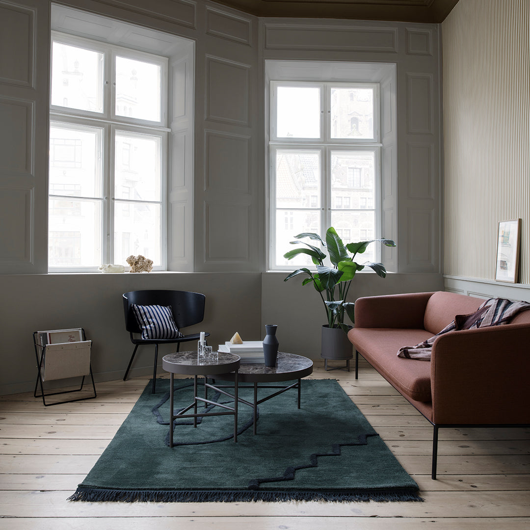 Green rug with zigzag pattern, complemented by a brown sofa and neutral-toned interior decor.
