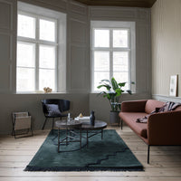 Green rug with zigzag pattern, complemented by a brown sofa and neutral-toned interior decor.