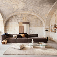 Brown sectional sofa with neutral cream and beige accents; textured beige rug and soft pillows add warmth.