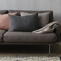 Gray, pink, and beige decorative pillows with subtle textures on a modern gray sofa and a cream throw blanket.