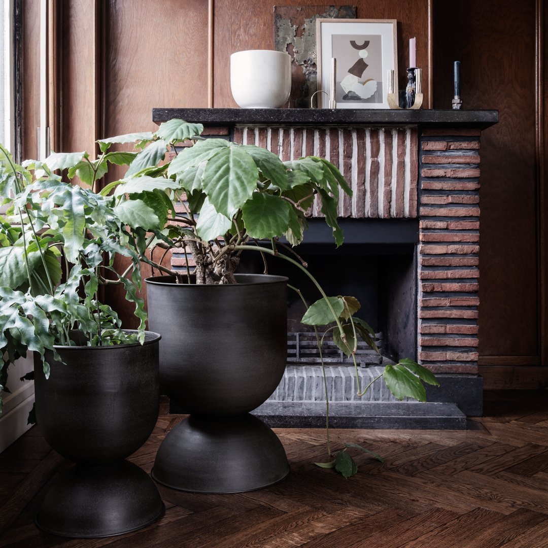 Black textured planters with a smooth finish, set against a warm wood and brick backdrop. Stylish indoor plant display.