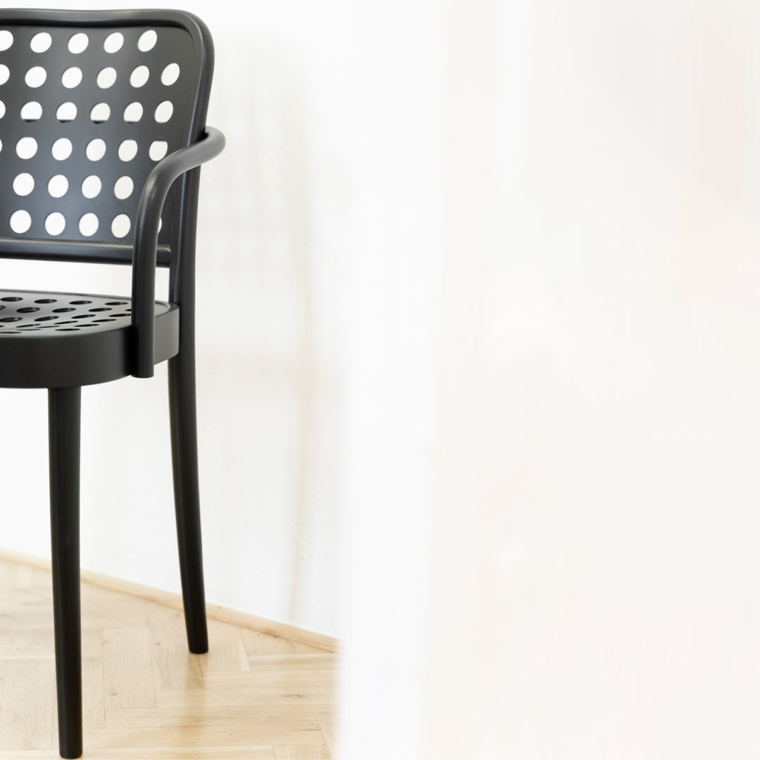 Black chair with a dotted pattern, featuring a sleek modern design and wooden floor background.
