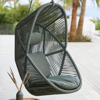 "Modern hanging chair in dark green with sleek geometric patterns and plush gray cushions for outdoor relaxation."