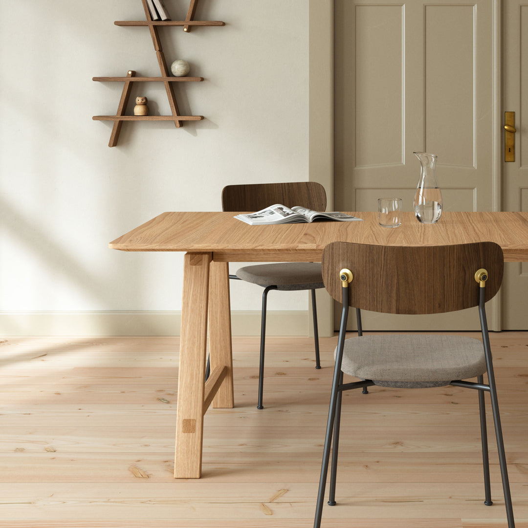 Natural wood table with sleek grain, complemented by neutral-toned chairs and soft pastel wall. Modern minimalist design.